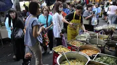 Karyawan perempuan membeli makanan sebelum mereka pergi bekerja di sebuah gang, yang terkenal dengan pedagang kaki lima dan pakaian, di pusat Bangkok, Thailand (8/11/2019). (AP Photo/Aijaz Rahi)