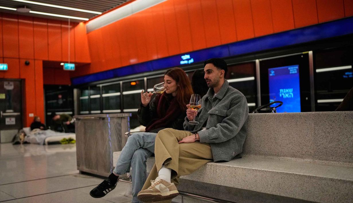 Sebagai informasi, serangan udara ini merupakan bagian dari perang yang meluas sejak akhir Februari 2026, yang dipicu oleh serangan udara Amerika Serikat bersama Israel terhadap Iran. Tampak dalam foto, orang-orang berlindung di stasiun metro bawah tanah saat sirene serangan udara memperingatkan datangnya rudal Iran di Tel Aviv, Israel, Sabtu, 7 Maret 2026. (AP Photo/Ohad Zwigenberg)