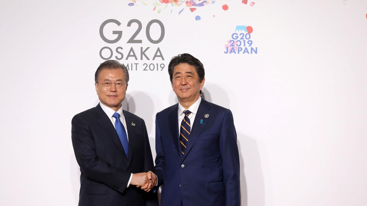 Presiden Korea Selatan (kiri) berjabat tangan dengan Perdana Menteri Jepang Shinzo Abe (kanan) di KTT G-20 tahun 2019 (AFP/Ludovic Marin)