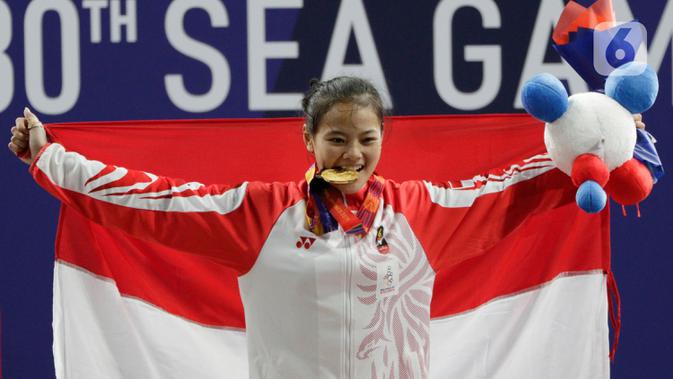 Lifter Windy Aisyah mengibarkan bendera usai mendapatkan medali emas SEA Games 2019 cabang angkat besi nomor 49 kg di Stadion Rizal Memorial, Manila, Minggu (1/12/2019). Windy Aisyah meraih emas dengan total angkatan 104 kg. (Bola.com/M Iqbal Ichsan)