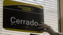 Pekerja kantor Western Union memasang tanda tutup pada hari terakhir bisnisnya di Havana, Kuba, Senin (23/11/2020). Penutupan yang didorong oleh sanksi keras AS itu akan membuat ribuan warga Kuba yang biasa menggunakan jasa perusahaan pengiriman uang tersebut kehilangan akses. (AP/Ismael Francisco)