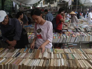 Seorang wanita mencari buku yang di dijual selama pameran buku bekas di Hanoi, Vietnam (26/10).( AFP Photo/Hoang Dinh Nam)