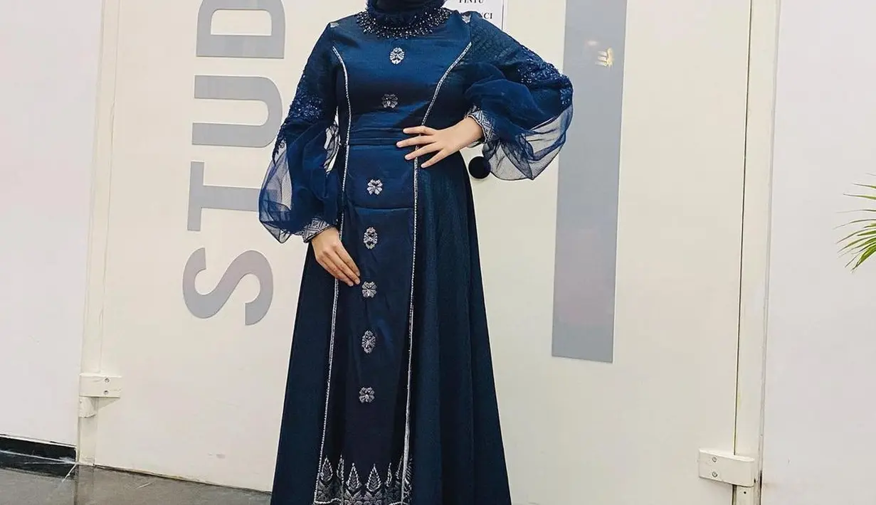 Gaun panjang warna navy dengan aksen puff pada lengan beri kesan elegan pada Putri saat tampil di acara Anugerah KPI 2022.