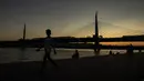Seorang wanita berjalan di dekat the Golden Horn atau tanduk emas di Istanbul (26/7/2019). Tanduk Emas merupakan jalur air perkotaan utama dan pintu masuk utama Bosphorus di Istanbul, Turki. (AP Photo/Emrah Gurel)