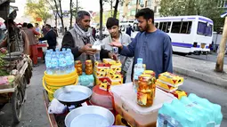 Dalam gambar yang diambil pada 5 April 2022, pelanggan membeli makanan berbuka puasa untuk berbuka puasa di pasar selama bulan suci Ramadhan di Kabul, Afghanistan. (Sahel ARMAN / AFP)