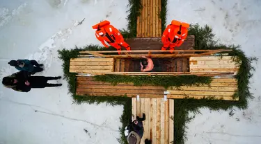 Petugas penyelamat mengamati seorang penganut Ortodoks Rusia yang berendam dalam air es saat perayaan tradisional Epiphany di Kronstadt, luar St. Petersburg, Rusia, 18 Januari 2023. Ribuan pengikut Gereja Ortodoks Rusia terjun ke sungai dan kolam es di seluruh negeri untuk menandai Epiphany, membersihkan diri dengan air yang dianggap suci untuk hari itu. (AP Photo/Dmitri Lovetsky)