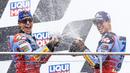 Pembalap Gresini Racing, Marc Marquez (kiri) dan Alex Marquez menyemprotkan sampanye saat melakukan selebrasi kemenangan di atas podium setelah MotoGP Jerman 2024, Minggu (07/07/2024) waktu setempat. (AFP/Radek Mica)