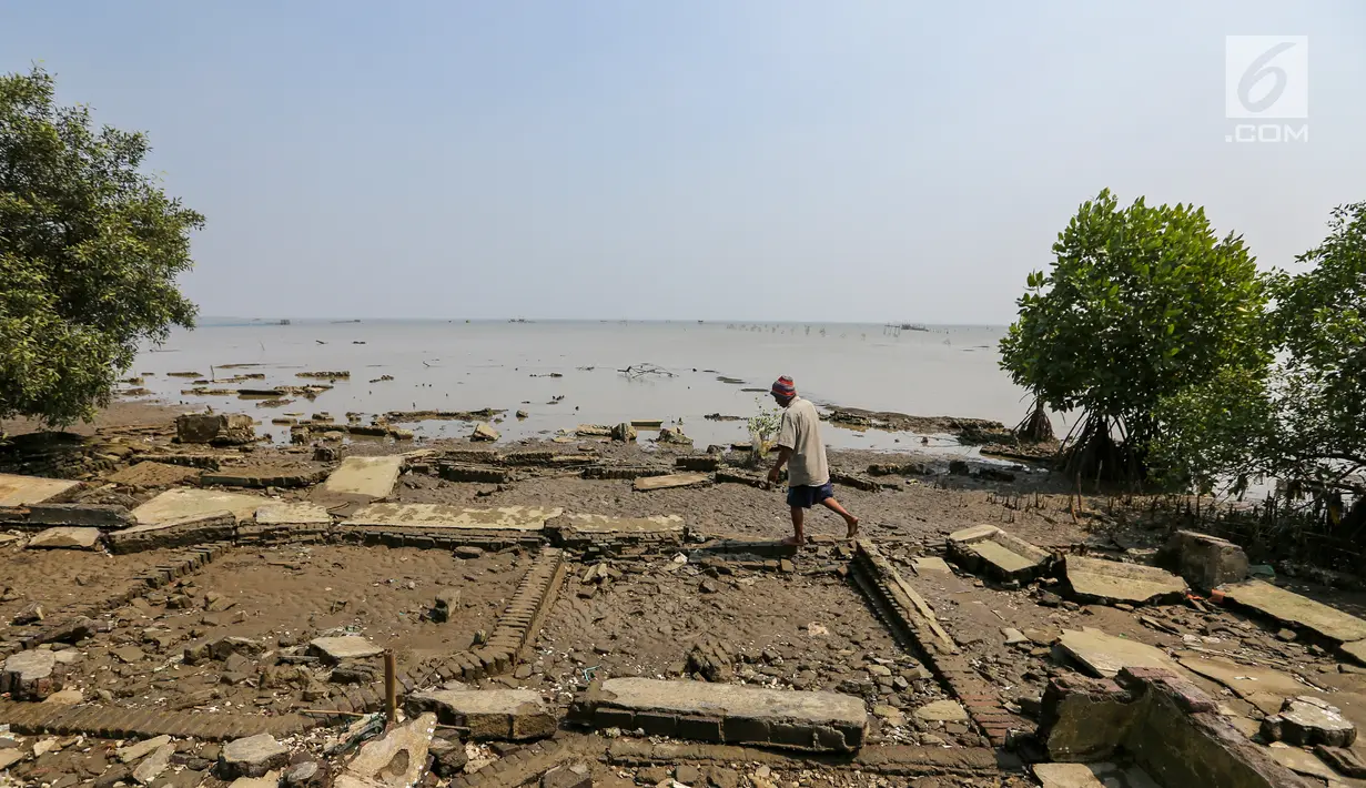 Warga melintas di atas puing bangunan yang terkikis akibat abrasi di Desa Pantai Mekar, Kecamatan Muara Gembong, Bekasi, Kamis (20/6/2019). Puluhan rumah warga di Kampung Muarajaya RT01/RW01 Desa Pantai Mekar hilang tersapu air saat terjadi abrasi selama 10 tahun. (Liputan6.com/Fery Pradolo)