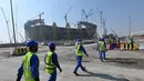 Pekerja melintas di depan pembangunan Stadion Lusail di Qatar, Jumat (20/12). Lusail akan menjadi stadion untyuk partai pembuka dan penutup piala dunia 2022 di Qatar. (AFP/Giuseppe Cacace)