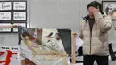 Seniman Lee Koo-Young menunjukkan lukisan Presiden Korsel, Park Geun-Hye tanpa busana yang dihancurkan di gedung Majelis Nasional, Seoul, Selasa (24/1). Lukisan itu dihancurkan kelompok konservatif dalam ajang ekshibisi lukisan parodi. (STR/YONHAP/AFP)