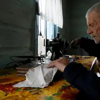 Mikhail Baburin (66) menggunakan mesin jahit di rumahnya di desa Mikhailovka di Siberia, 5 Desember 2016. Selama 10 tahun terakhir, Baburin tinggal sendirian di desa yang letaknya sangat terpencil. (REUTERS/Ilya Naymushin)