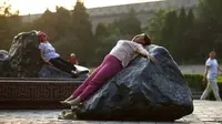 Ternyata berbaring di batu-batu besar saat terik matahari tengah menjadi tren kesehatan musim panas para perempuan di Tiongkok.