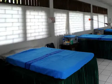 Petugas gugus tugas Covid-19 RW 03 menyemprotkan desinfektan pada tempat tidur untuk isolasi mandiri di Gedung Sasana Krida Karang Taruna, Kelurahan Pondok Labu, Jakarta, Selasa (19/1/2020). Gedung itu disulap oleh warga setempat untuk dijadikan tempat isolasi mandiri. (merdeka.com/Arie Basuki)