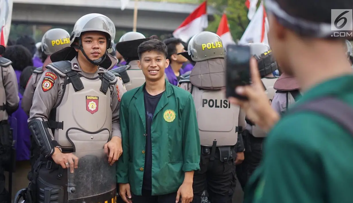 Seorang mahasiswa berfoto dengan polisi yang mengamankan aksi unjuk rasa Badan Eksekutif Mahasiswa Seluruh Indonesia (BEM SI) di sekitar gedung DPR RI, Jakarta, Selasa (1/10/2019). (Liputan6.com/Immanuel Antonius)