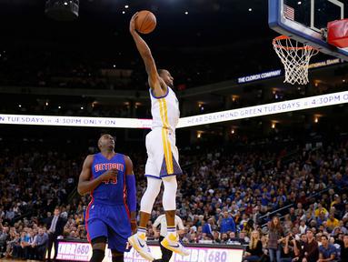 Pebasket Golden State Warriors Andre Iguodala melakukan Dunk saat dibayangi pebasket Detroit Pistons Anthony Tolliver di ORACLE Arena, California, Senin (9/11/2015). Warriors menang 109-95. (Getty Images/AFP/Ezra Shaw)