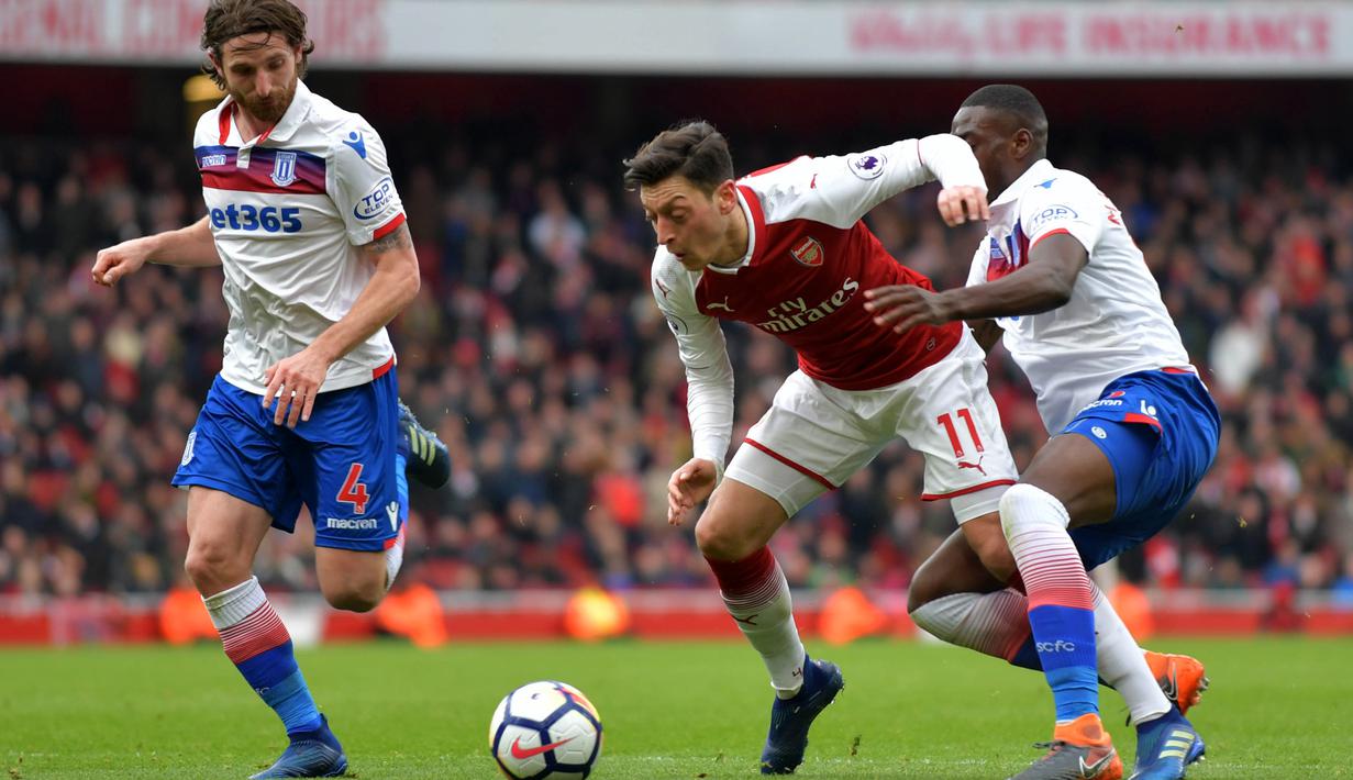 Gelandang Arsenal, Mesut Ozil, ditarik oleh bek Stoke Bruno Martins Indi, pada laga Premier league di Stadion Emirates, London, Minggu (1/4/2018). Arsenal menang 3-0 atas Stoke. (AFP/Oliver Greenwood)