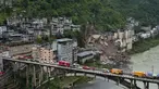 Kendaraan penyelamat bersiaga di jembatan saat tim penyelamat melakukan operasi pencarian dan penyelamatan di lokasi tanah longsor di Kabupaten Pengshui, Chongqing, Tiongkok barat daya, Sabtu, 18 Juli 2026. (AP Photo/Andy Wong)