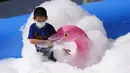 Seorang anak yang mengenakan masker bermain dengan balon berbentuk flamingo dalam gelembung saat Hari Anak Internasional di sebuah mal di Beijing, China, Selasa (1/6/2021). Partai Komunis China melonggarkan batas kelahiran untuk memungkinkan semua pasangan memiliki tiga anak. (AP Photo/Ng Han Guan)