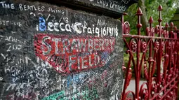 Graffiti digambarkan di gerbang Strawberry Field yang baru dibuka untuk umum di Liverpool, Rabu (18/9/2019). Strawberry Field adalah nama sebuah panti Salvation Army di sekitar sudut rumah masa kecil John Lennon yang menjadi populer dan kini dibuka untuk umum usai 70 tahun ditutup. (Paul ELLIS/AFP)
