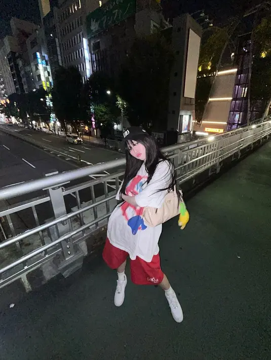 Gaya boyish Y2K ala Karina aespa. Ia tampil kece memadukan boxy t-shirt dengan celana pendek ¾, sneakers, cap, dan shoulder bag dengan doll charm. [@katarinabluu].