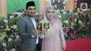 Sepasang pengantin menunjukkan buku nikah seusai prosesi ijab-kabul di KUA Pamulang, Tangerang Selatan, Selasa (22/2/2022). Sebanyak 10 pasangan menjalankan akad nikah di KUA Pamulang pada hari ini yang dianggap memiliki tanggal cantik. (merdeka.com/Arie Basuki)