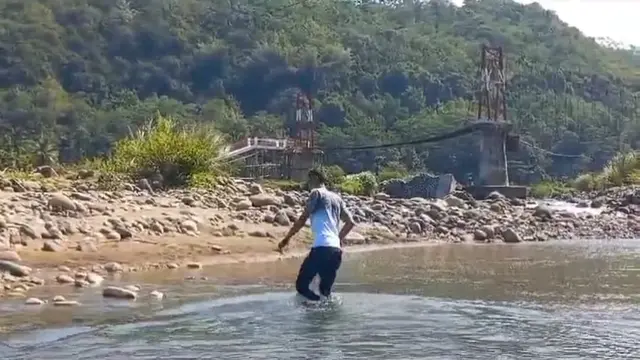 Salah satu warga terpaksa menyebrangi sungai Cirompang, Desa Jagabaya Kecamatan Mekarmukti, Garut, karena akses satu-satunya jembatan rawayan yang terputus belum diperbaiki. (Liputan6.com/Jayadi Supriadin)